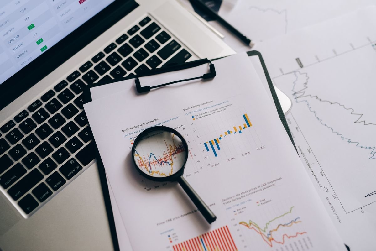 An overhead view of financial charts and a laptop next to a magnifying glass