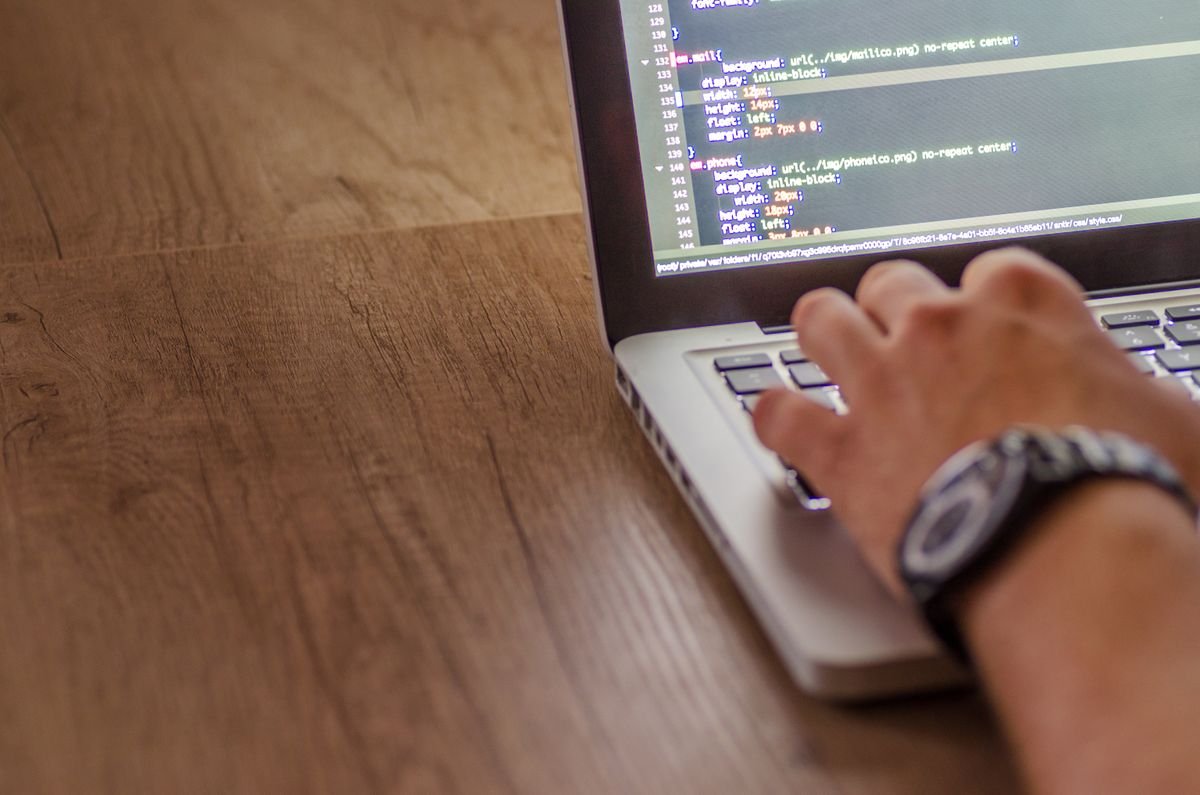 A person codes on a laptop, focused on web development