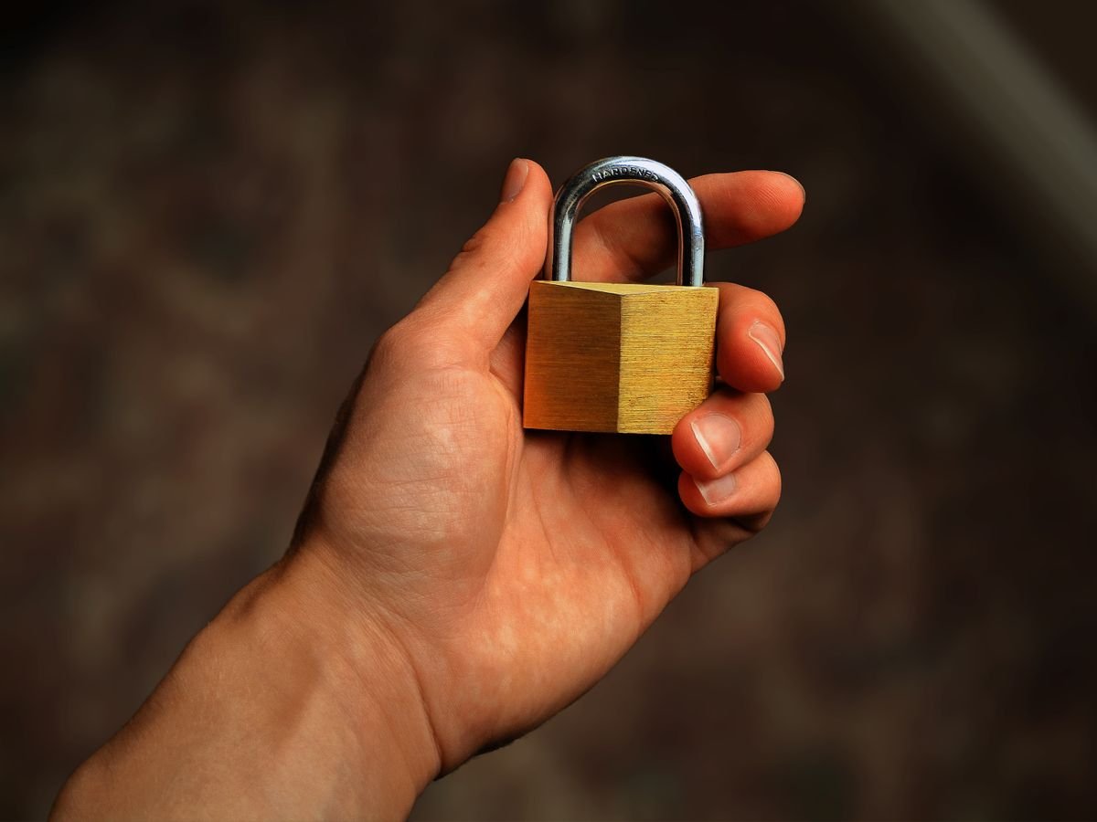 A hand holds a brass padlock