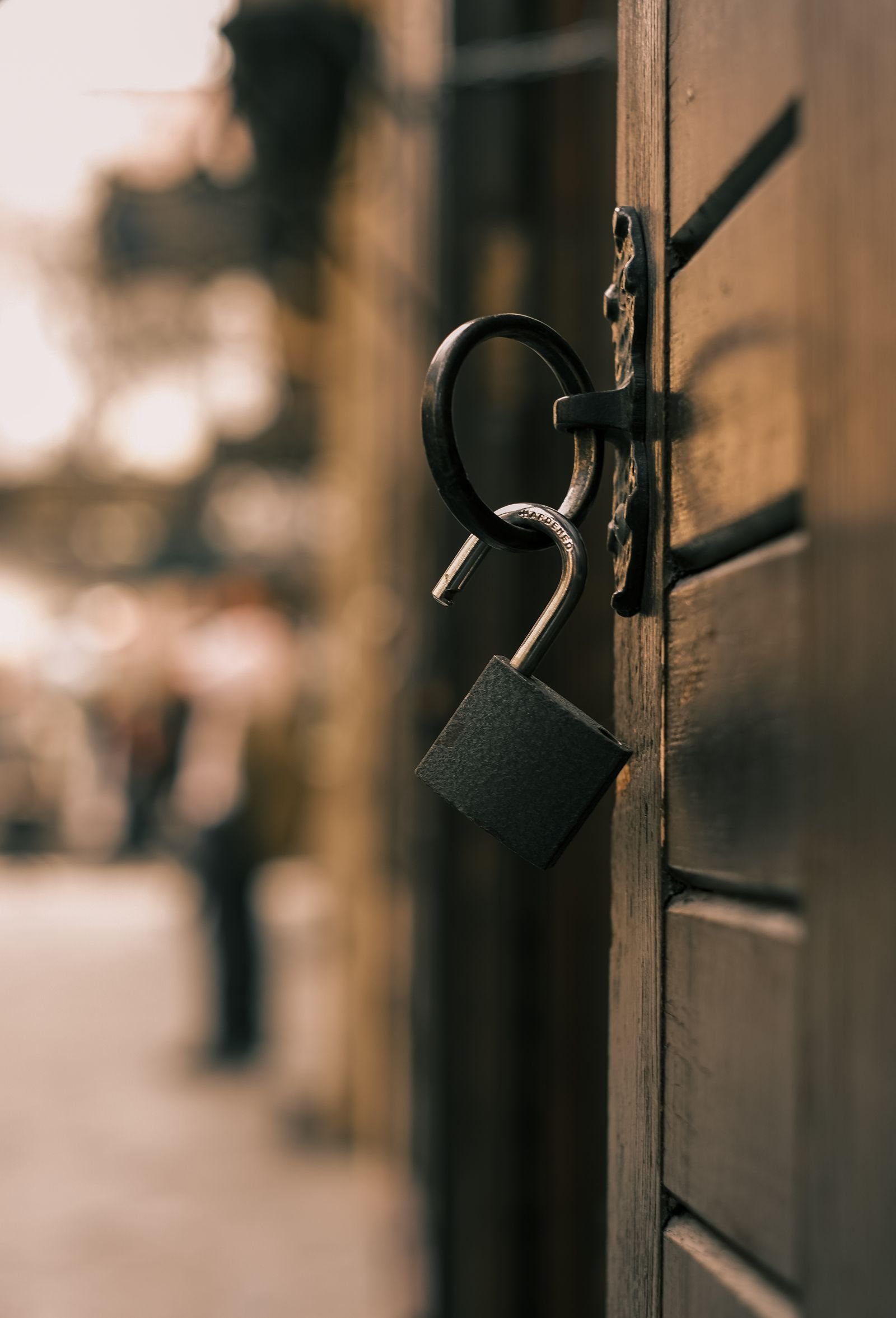 An unlocked padlock hangs open on a wooden door