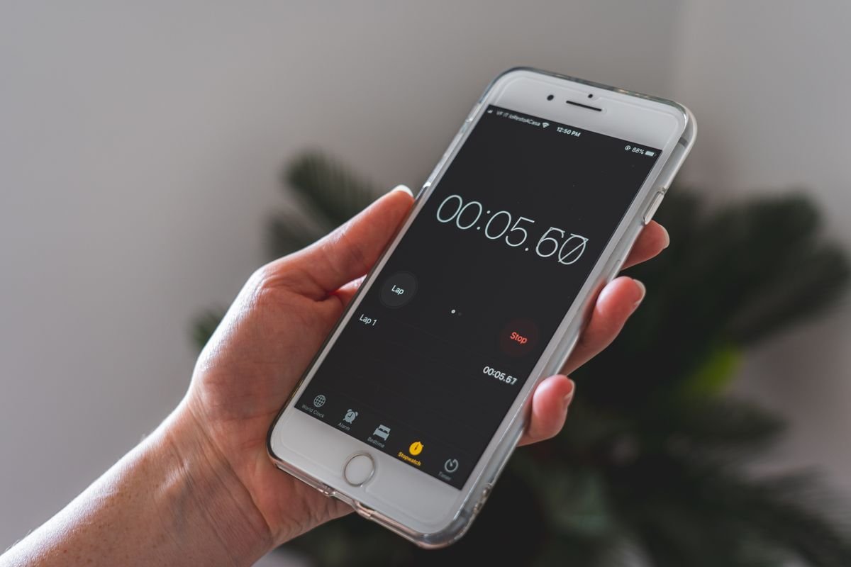 A hand holds a smartphone running a stopwatch app