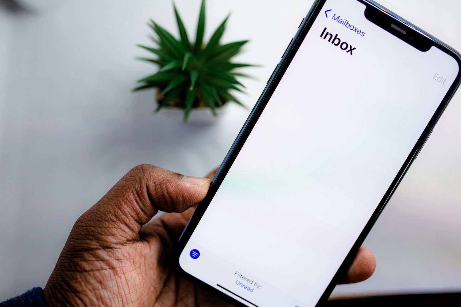 A hand holds a smartphone showing an email inbox